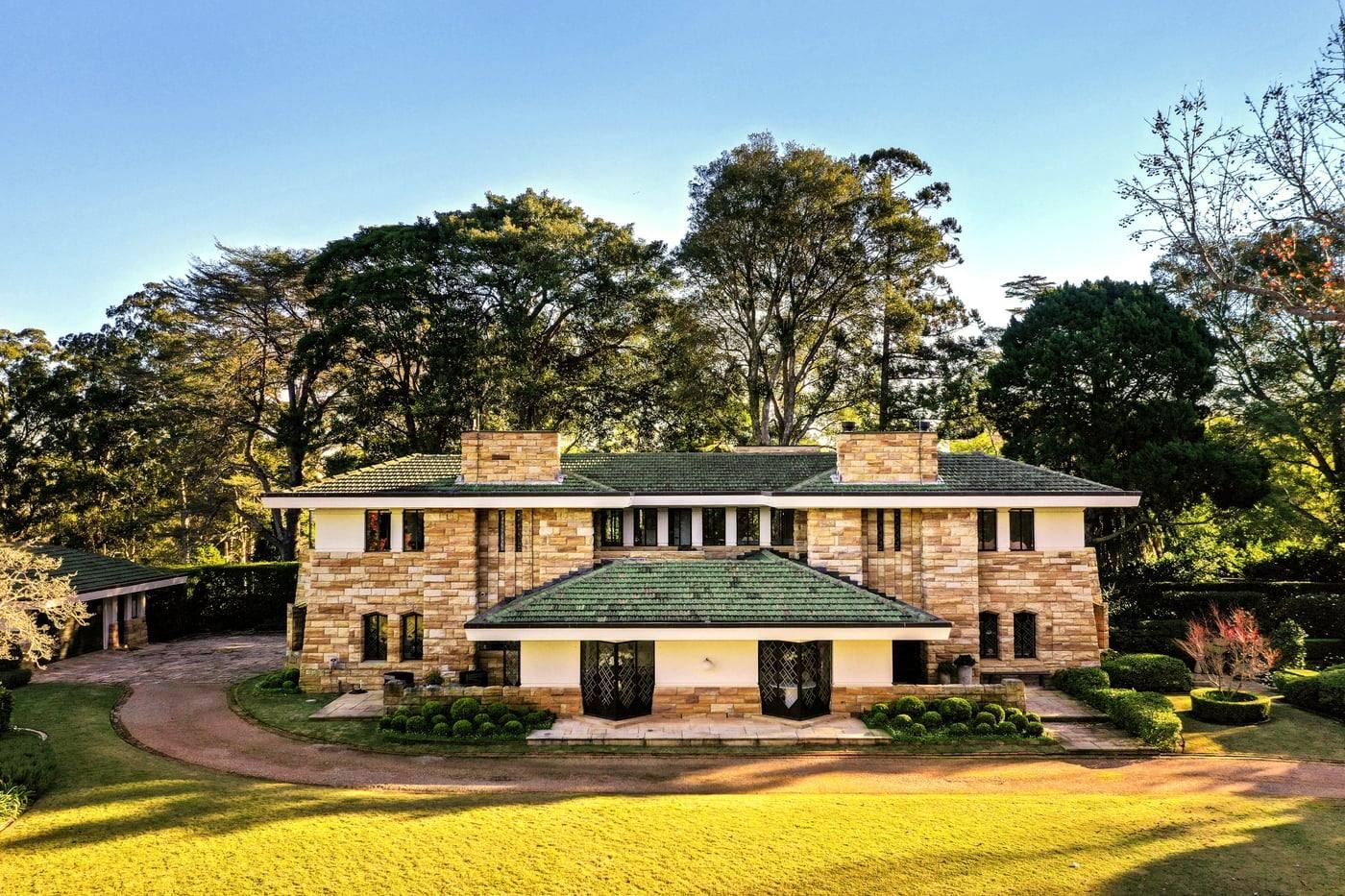 Coppins, the 1936 Walter Burley Griffin sandstone residence at dusk across its lawns
